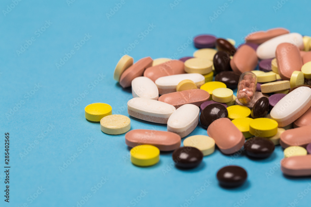 many scattered Colorful medical pills on pastel blue background