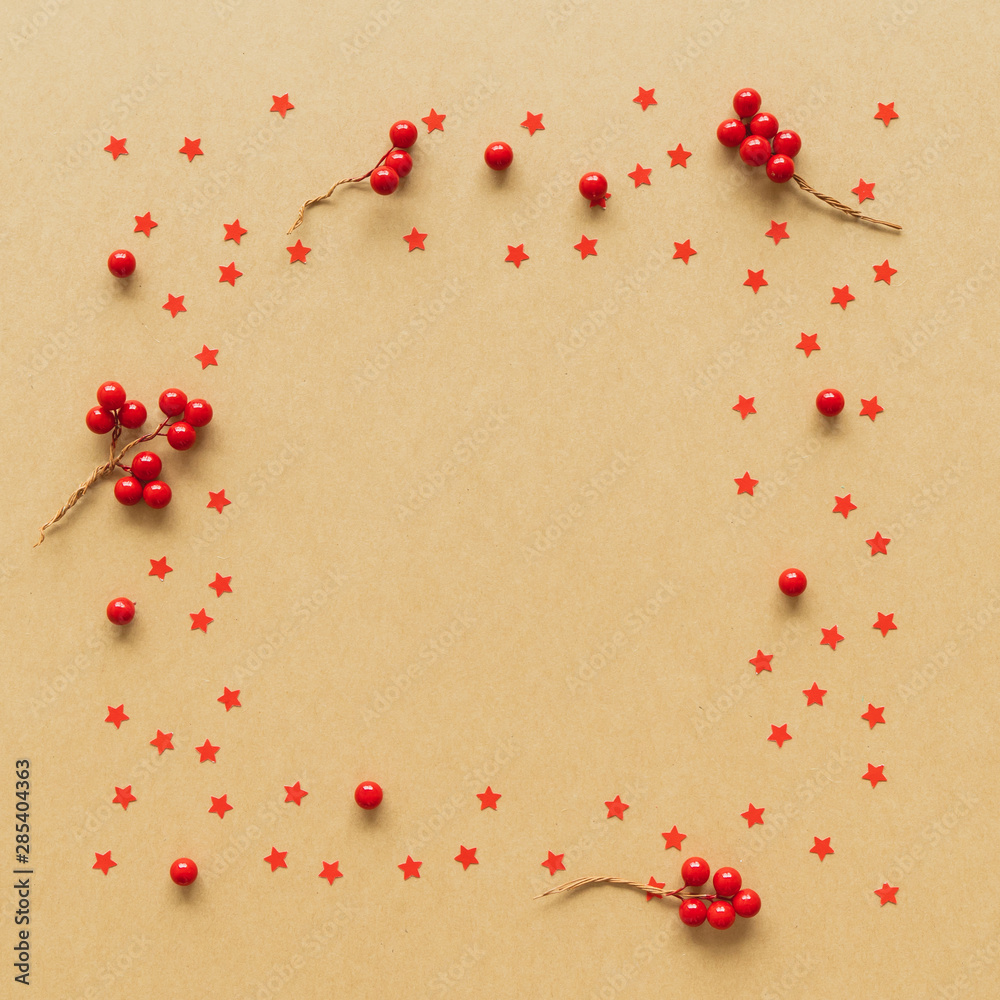 Christmas Flame made from red berries and star on paper background. Flat lay, top view.