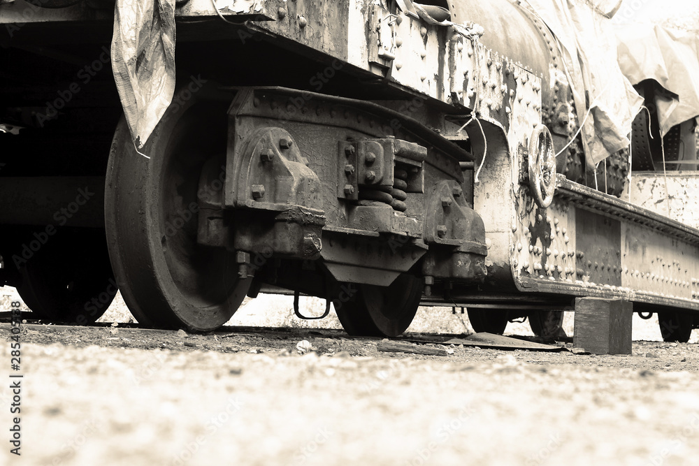 Old freight train locomotive wagon, close-up of the wheels, on track line covered with tarpaulin.  With colour toning.