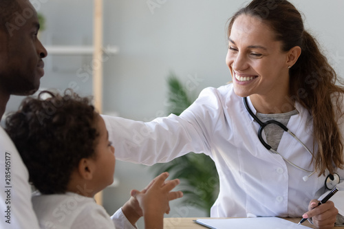 Friendly female doctor stroke head of cute african child boy