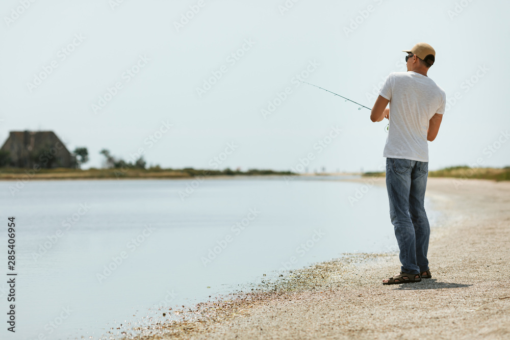 Young man fishing at sea from the shore. fisherman uses spinning Young man fishing at sea from the shore. fisherman uses spinning