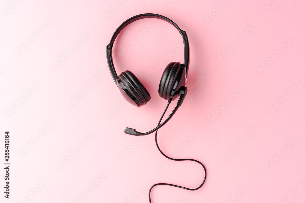 Call center concept. Helpdesk headset on pink desktop with copyspace Call center concept. Helpdesk headset on pink desktop with copyspace