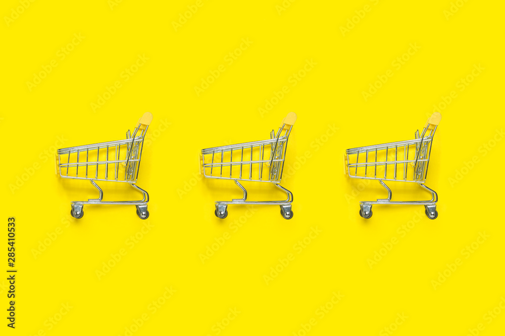 Three shopping trolley on a yellow background. Concept of shopping, discount, sale. Flat lay, top view Three shopping trolley on a yellow background. Concept of shopping, discount, sale. Flat lay, top view