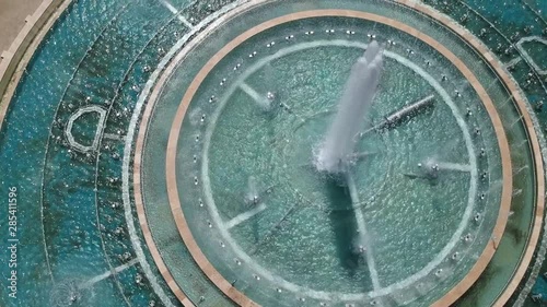 drone flying over a big fountain, showing the sun's reflections and a small girl running to her parents.mp4