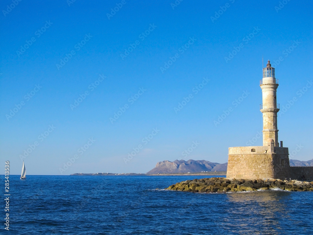 Photo of iconic old Venetian lighthouse in old harbour of Chania. Crete island, Greece