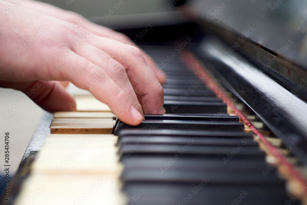 Closeup shot of male hands on the piano keyboard.