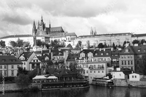 View of Mala Strana, St. Vitus Cathedral and Prague castle over Vltava river in black and white.