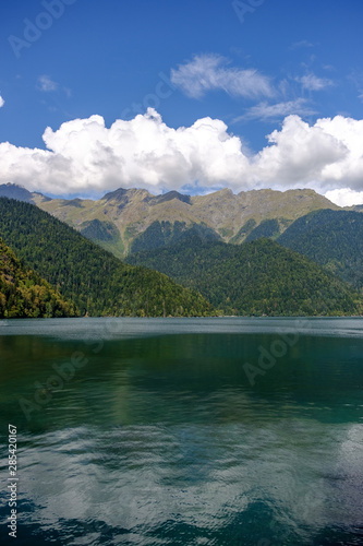 Ritsa lake and mountains in Abkhazia. White clouds in the blue sky over the mountains.