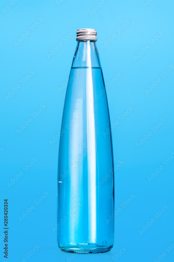 Glass water bottles on a light blue background Glass water bottles on a light blue background