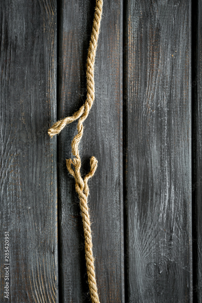 Tearing the rope under stress on wooden background top view copyspace Tearing the rope under stress on wooden background top view copyspace