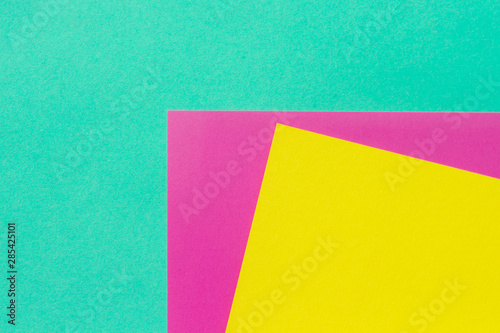 Abstract geometric paper background. Neon gradient of mint, purple, and yellow trendy colors. Geometric vibrant colors textured flat lay.