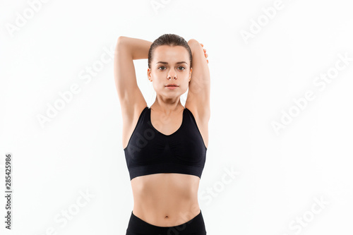 Young sporty blond woman in a black sportswear stretching before exercising isolated over white background.