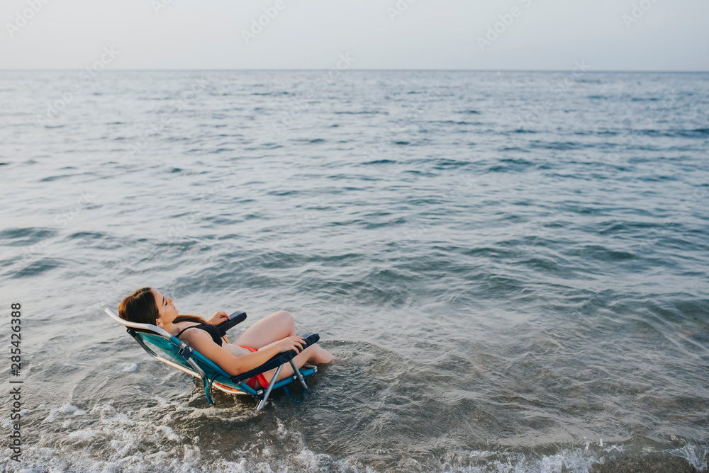 Naklejka premium woman sitting on a beach chair over the sea