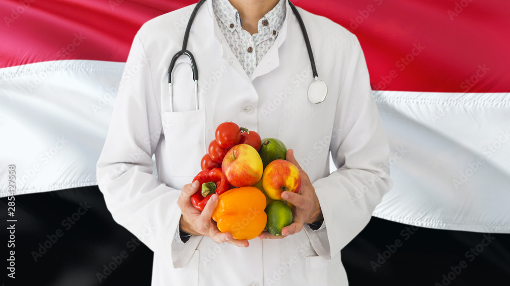 Doctor is holding fruits and vegetables in hands with Egypt flag background. National healthcare concept, medical theme. Doctor is holding fruits and vegetables in hands with Egypt flag background. National healthcare concept, medical theme.