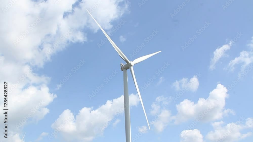 Energy turbine against a blue sky with white clouds - centered shot Energy turbine against a blue sky with white clouds - centered shot