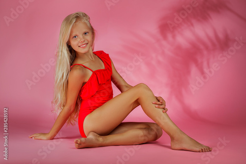 Obraz na płótnie cute little baby girl in a red swimsuit posing on a pink background