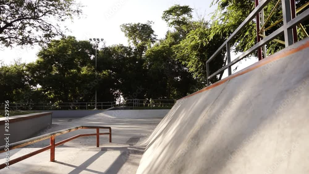 Roller skater ride in park. Boy legs in in-line hard shell boots blades. Doing tricks. Young man spending his leisure time in the skate park. Sliding on the high angle wall on rollers. Front view