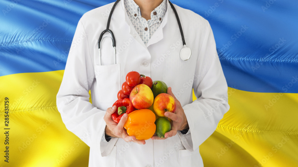 Doctor is holding fruits and vegetables in hands with Ukraine flag background. National healthcare concept, medical theme. Doctor is holding fruits and vegetables in hands with Ukraine flag background. National healthcare concept, medical theme.