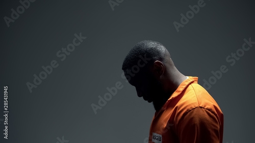 Upset african american prisoner feeling quilt and shame for committing crime photo