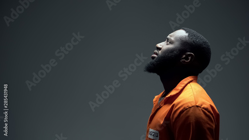 Fotografie, Obraz Afro-american imprisoned male praying looking up at light, talking to god, faith