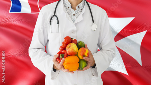 Doctor is holding fruits and vegetables in hands with Wallis And Futuna flag background. National healthcare concept, medical theme.