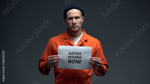 Caucasian prisoner holding Justice reform now sign, human rights protection photo