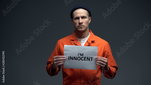 European imprisoned male holding I am innocent sign in cell, asking for justice photo