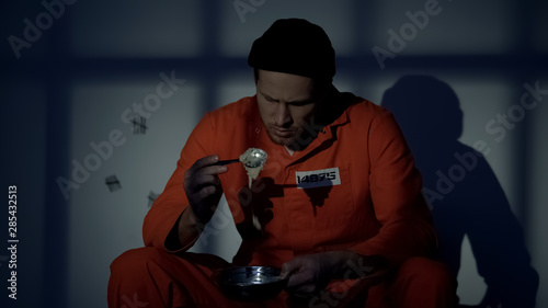 Quadro su tela Upset imprisoned man holding plate with disgusting food, human rights violation