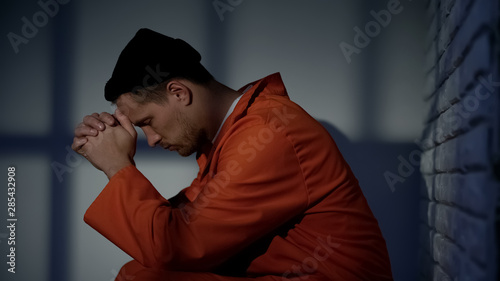 Photos Caucasian imprisoned male praying in cell, feeling guilty and asking for mercy