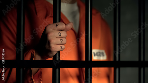 Fotografia Hope word on imprisoned man fingers, holding jail bars, dream about freedom