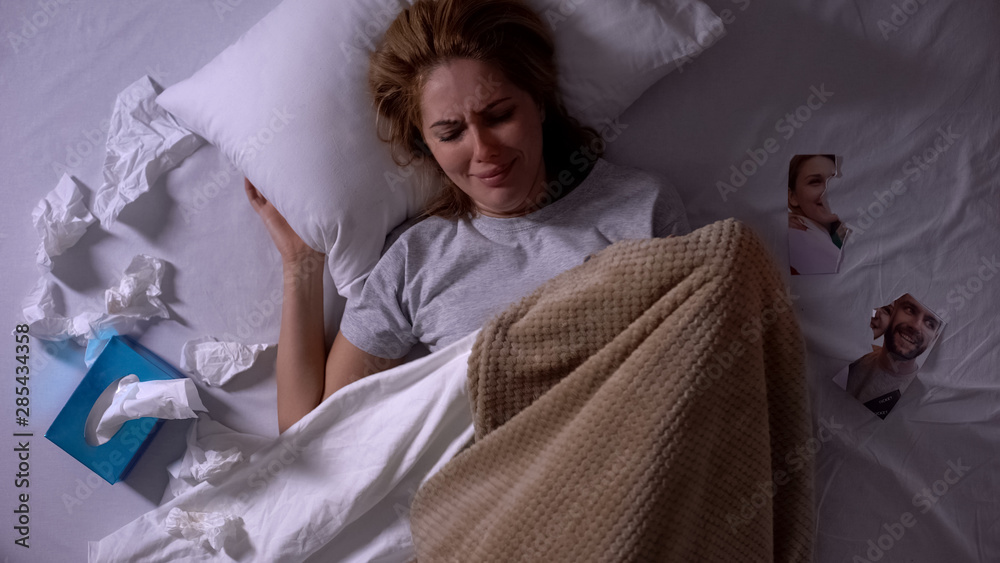 Φωτογραφία Woman crying lying in bed with tissues, torn photo of ex-boyfriend beside, break
