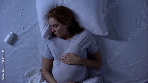 Photography Unconscious pregnant lady lying in bed, pills intoxication, suicide attempt