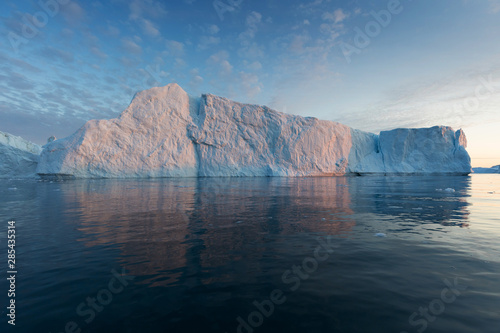 Nature and landscapes of Greenland or Antarctica. Travel on the ship among ices. Studying of a phenomenon of global warming Ices and icebergs of unusual forms and colors Beautiful midnight sun on ship © Michal