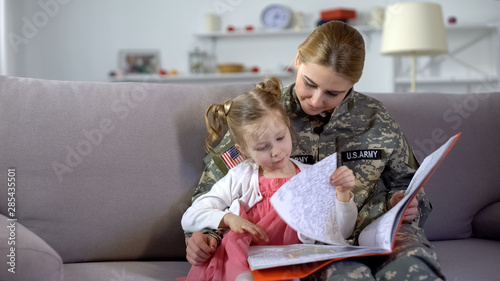 Mom in military uniform looking at drawings in coloring book together, leisure