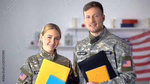 Obraz na plátne Female and male US military students with folders smiling at camera, education