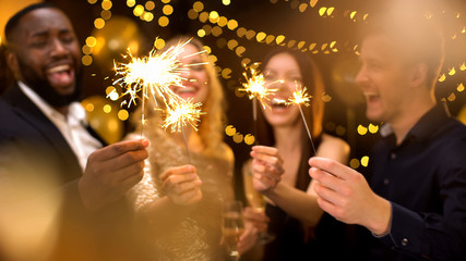 Overjoyed young people celebrating new year, holding bengal lights, having fun