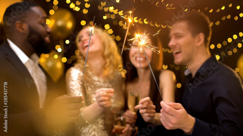 Photography Four joyful colleagues holding burning sparklers and champagne glasses, party