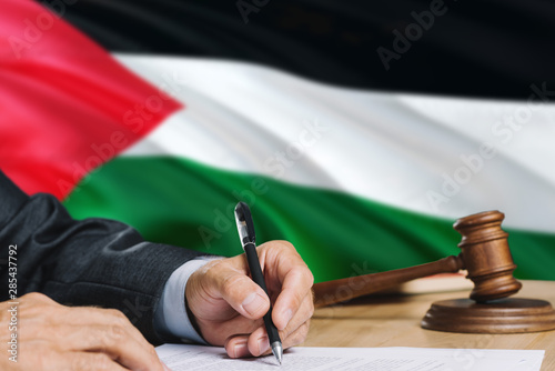 Принти на полотні Judge writing on paper in courtroom with Palestine flag background