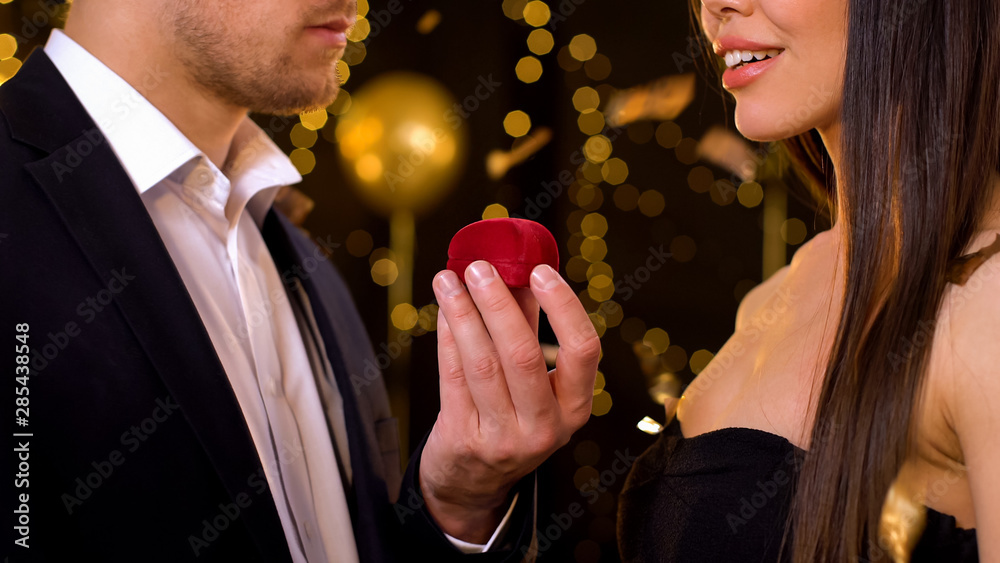 Male holding gift box with jewelry, presenting girlfriend for birthday at party - obrazy, fototapety, plakaty 