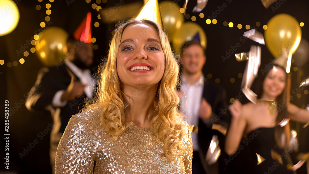 Cheerful young woman smiling on camera at party, celebrating New Year, fun Cheerful young woman smiling on camera at party, celebrating New Year, fun