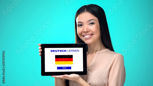 Female holding tablet with learn german application, ready to start course