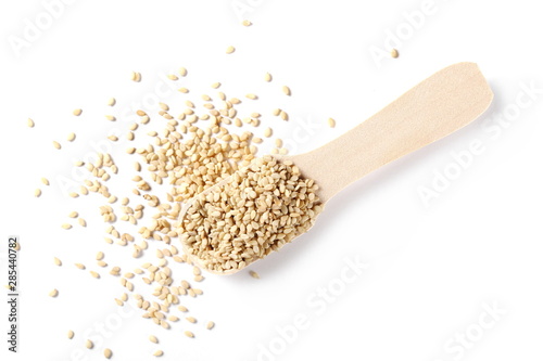 Organic integral sesame seeds with wooden spoon isolated on white background, top view