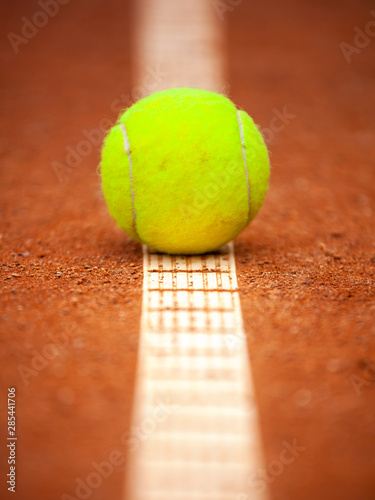 Fototapeta Naklejka Na Ścianę i Meble -  A yellow tennis ball lies on the clay court.
