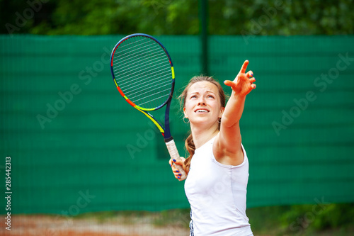 Young female tennis player serving.