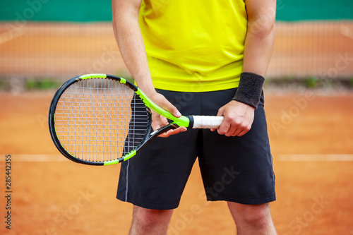 Midsection of male tennis player holding the racket. © Dmytro Panchenko