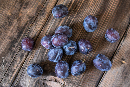 Fresh organic plums on old wooden table.