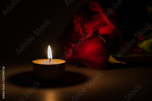 Fotografia tealight candle and red rose at midnight