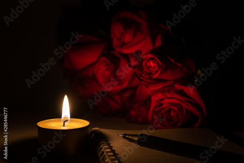Foto Tealight candle, pen, note book and roses