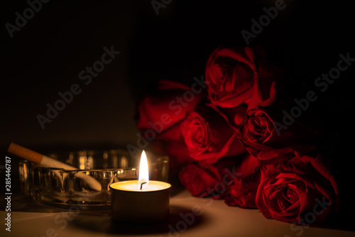 Konstfotografi Tealight candle, red roses, cigarette and ashtray