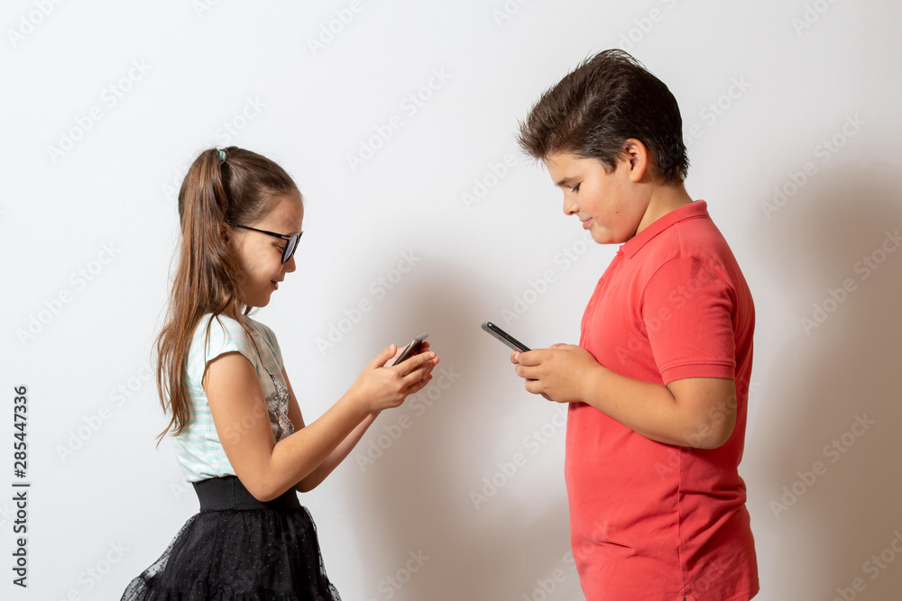 A little girl and a boy looking at smartphones. Children are passionate about social networks